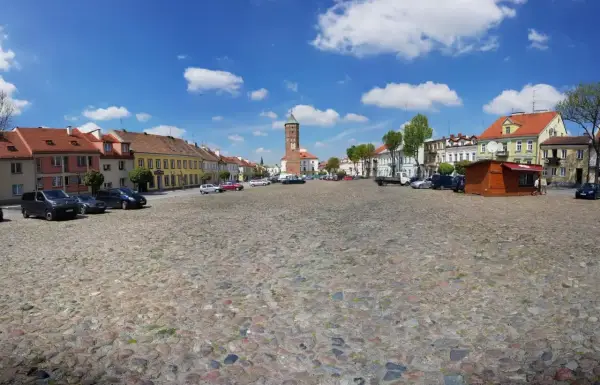 Rynek w Pułtusku z brukowaną nawierzchnią, kolorowymi kamienicami i charakterystyczną wieżą.