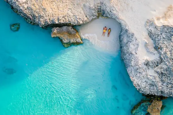 Para na plaży na wyspie Aruba, otoczonej turkusową wodą i skalistymi klifami. Idealne miejsce na relaks.