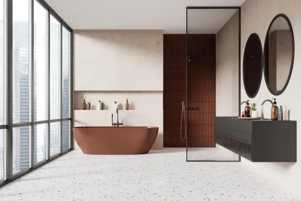 Salle de bain moderne avec baignoire rouille, douche en briques rouges et lavabo suspendu. Le sol en terrazzo offre une belle dimension carrelage.