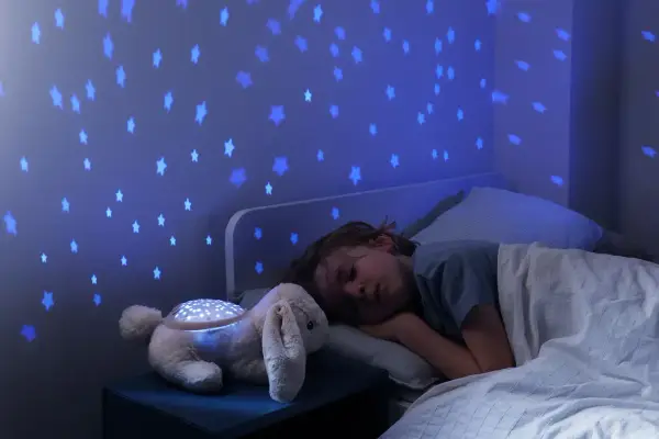 Uroczy króliczek z projektorem dla niemowlaka rzuca na ścianę niebieskie gwiazdki, tworząc magiczną atmosferę do snu.