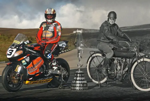 Conor Cummins junto a su moto de carreras y un trofeo, junto a un piloto histórico en una Indian.
