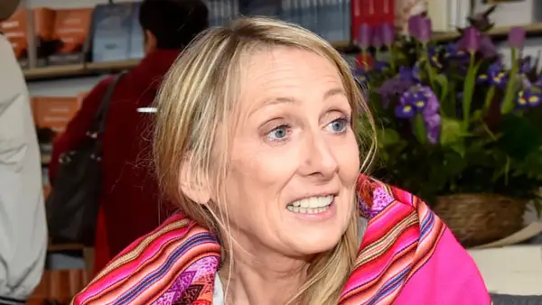 Beata Pawlikowska z kolorowym szalem na tle książek i kwiatów.