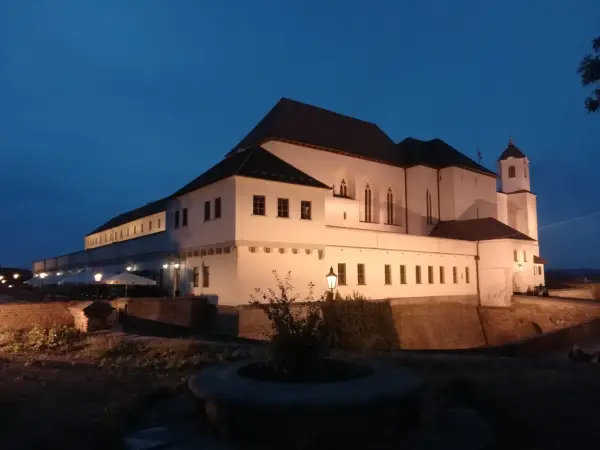 Brno zamek nocą, oświetlony, z wieżą i murami obronnymi.