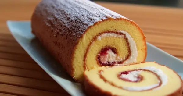 En saftig glutenfri rulltårta med sylt och grädde, pudrad med florsocker.