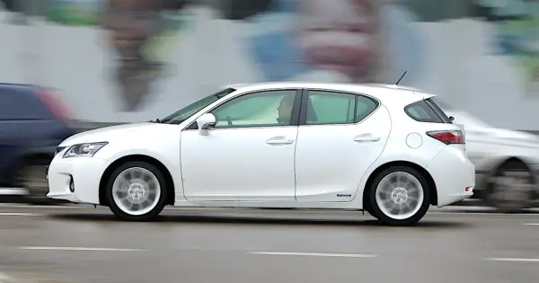 Biały Lexus CT200h w ruchu ulicznym, z rozmytym tłem i innymi samochodami.