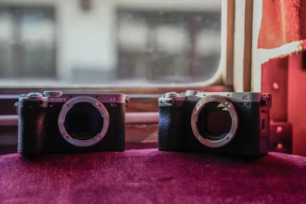 Dwa aparaty Sony Alpha, jeden a7c i drugi a7CR, leżą obok siebie na aksamitnym materiale.