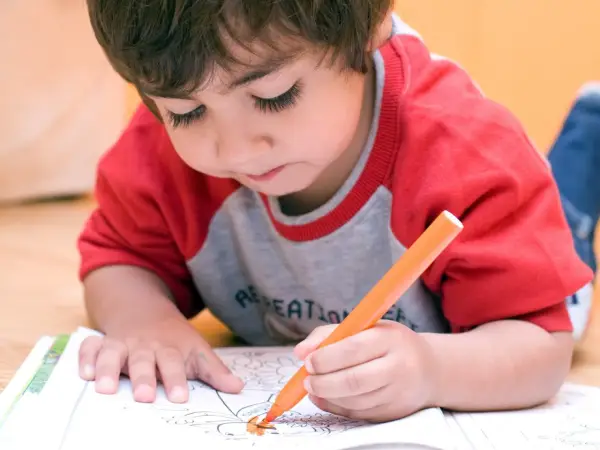 Bambino concentrato colora un disegno. A che età si capisce se un bambino è iperattivo? Osservare la sua attenzione e calma.