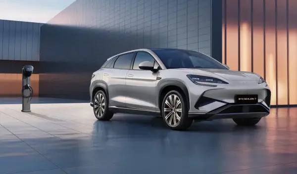 Srebrny SUV BYD Seal U stoi obok ładowarki na tle nowoczesnego budynku.