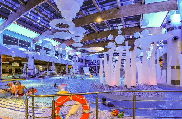 Wesoła zabawa w aquaparku w Sopocie, mnóstwo ludzi cieszy się basenem i atrakcjami. Warto sprawdzić aquapark Sopot opinie przed wizytą.