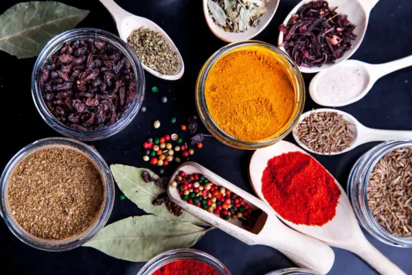 Kolorowe przyprawy, w tym kurkuma, papryka i kmin rzymski, ułożone na czarnym tle. Idealne do przygotowania aromatycznego garam masala przepis.