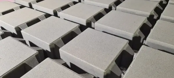 Szare, betonowe kostki brukowe ułożone w rzędach, gotowe do budowy ścieżki. Różne rodzaje kostki brukowej czekają na zastosowanie.