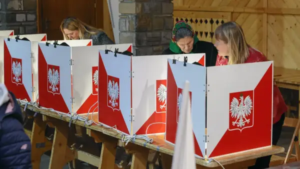 Kobiety głosują w wyborach do sejmu. Kabiny wyborcze ozdobione są godłem Polski.