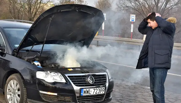 Zmartwiony kierowca przy dymiącym silniku. Zastanawia się, ile kosztuje wyjęcie silnika z samochodu po awarii.