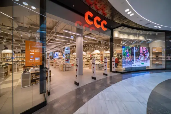 Wejście do sklepu CCC z widocznym logo, półkami z butami i ekranem LED.