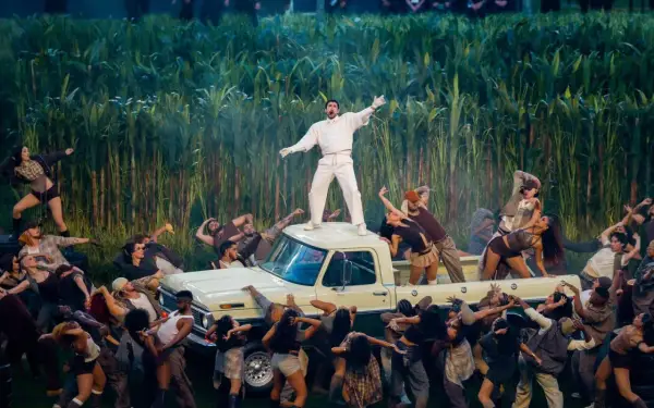 Super Bowl-artister dansar runt en pickup bland majsstjälkar. En artist står på taket.