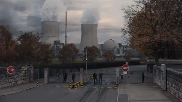 Mroczna elektrownia z chmurami pary nad chłodniami. Strażnicy przy bramie, nie wiadomo, kto jest kim.