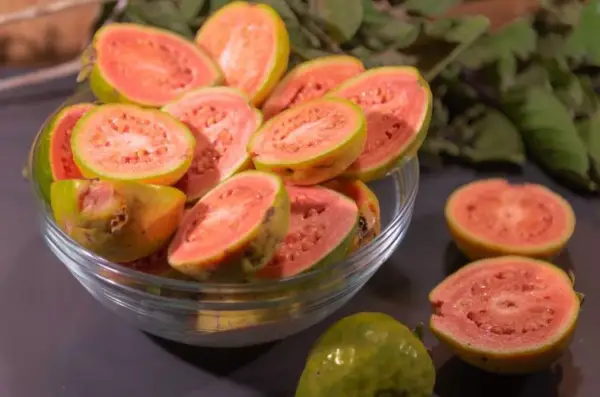 Kusząca guawa jak jeść? Pokrojone owoce w misce i na blacie, gotowe do degustacji.