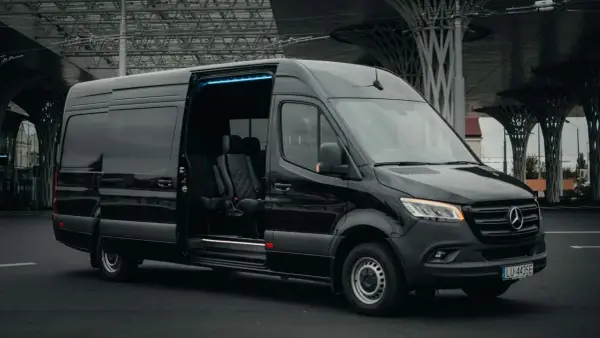 Czarny Mercedes Sprinter z otwartymi drzwiami, wnętrze z wygodnymi fotelami. Zastanawiasz się, ile kosztuje bus do Francji?