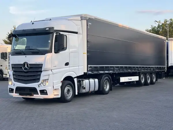 Biały Mercedes Actros MP4 z czarną plandeką naczepy Krone, gotowy do trasy.
