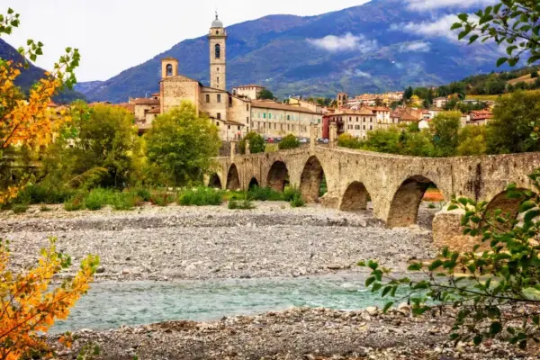 Ponte Gobbo a Bobbio, borgo dei borghi, con il fiume e le montagne sullo sfondo.