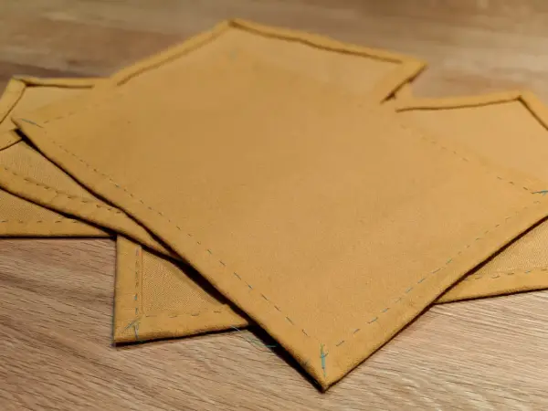 Serviettes de table en tissu ocre, finitions soignées. Idéal pour un tuto serviette de table facile à réaliser.