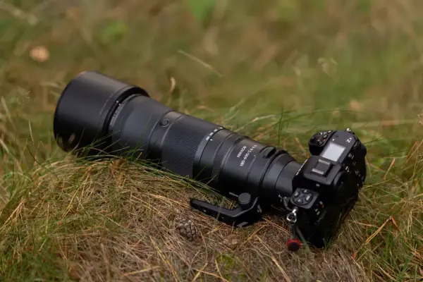 Profesjonalny aparat Nikon Z8 z obiektywem Nikkor 180-600mm leży na trawie. To co to jest aparat, to narzędzie do uwieczniania chwil.