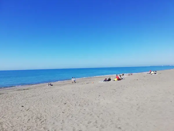 Słoneczny dzień na plaży w Marina di Bibbona. Ludzie odpoczywają na piasku, a morze lśni w słońcu.