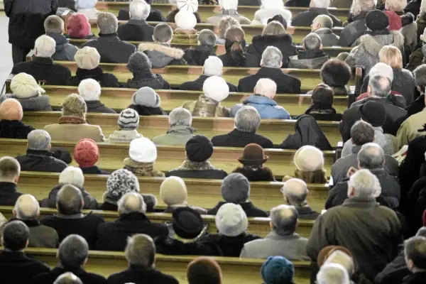 Ludzie siedzą w kościele, zastanawiając się, ile kosztują msze gregoriańskie. Wszyscy ubrani są ciepło, przygotowani na zimno.