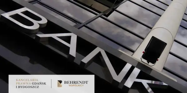 Litery "BANK" na fasadzie budynku, odbijające się w szklanej elewacji.