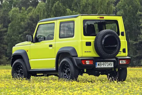 Jaskrawożółty Suzuki Jimny na tle łąki z żółtymi kwiatami. Sprawdź aktualną suzuki jimny cena i wybierz się na przygodę!