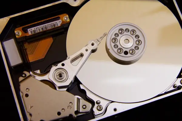 Vue rapprochée de l'intérieur d'un disque dur de PC, montrant le plateau, la tête de lecture/écriture et le moteur. L'emplacement du disque dur est essentiel pour le stockage des données.