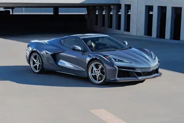 Szary Chevrolet Corvette Stingray z nowoczesnym designem, zaparkowany na tle betonowej architektury.