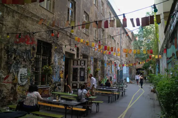 En livlig innergård i Prenzlauer Berg, Berlin, med väggmålningar, ljusslingor och sittplatser utomhus.
