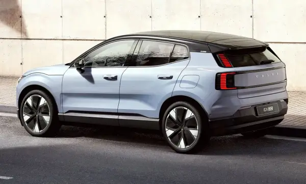 Nowy, elektryczny Volvo EX30 w kolorze jasnoniebieskim prezentuje się nowocześnie na tle betonowej ściany.