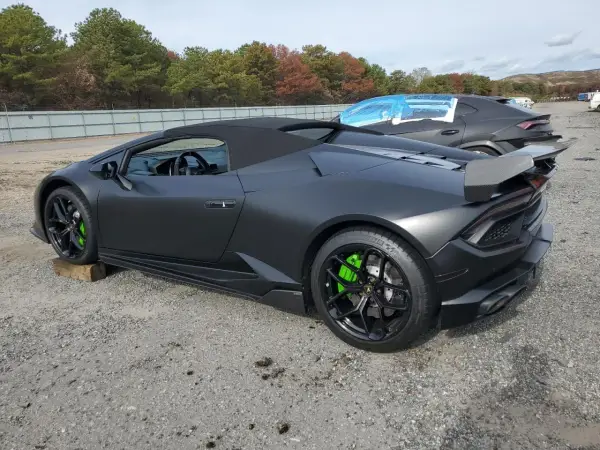 Matowy czarny lambo huracan z jaskrawozielonymi zaciskami hamulcowymi stoi na żwirowym placu.