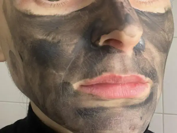 Twarz z nałożoną czarną maseczką rewitalizującą Avon. Skóra wokół ust i nosa jest odsłonięta.