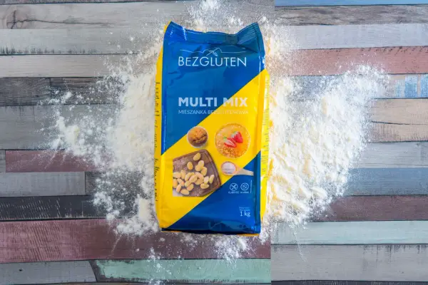 Opakowanie mąki bez glutenu "Multi Mix" rozsypane na drewnianym blacie. Idealna do wypieków dla osób na diecie bezglutenowej.