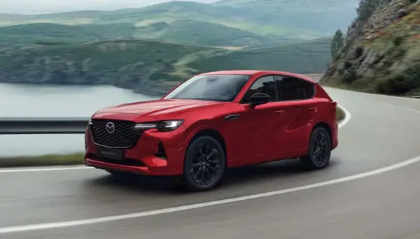 Czerwona Mazda CX-60 3.3 diesel pokonuje zakręt na malowniczej drodze.