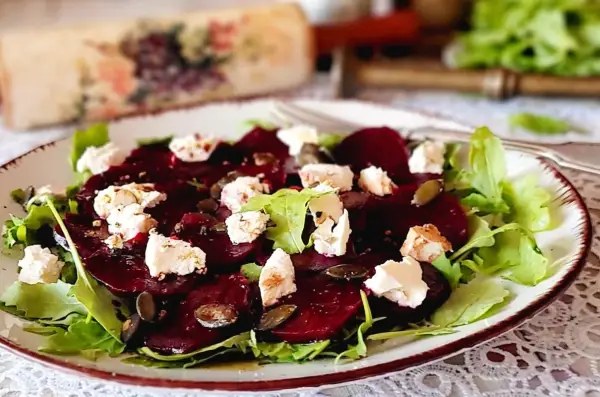 Pyszne carpaccio z buraka z serem feta, rukolą i pestkami dyni na talerzu.
