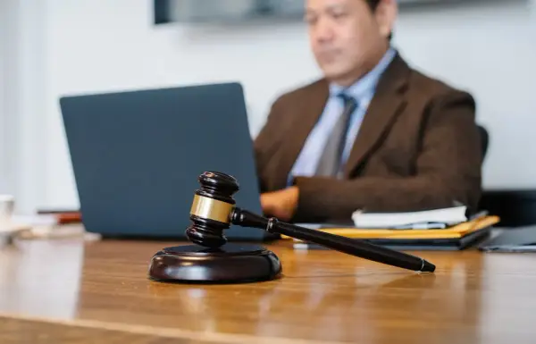Sądowy młotek na biurku, prawnik pracuje przy laptopie. Dyskrecja w ujawnieniu informacji o zadłużeniu osobom trzecim.