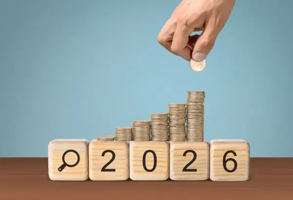 Klocki z napisem "2026" i lupą, na nich rosnące stosy monet. Czy to podpowiedź, ile zarabia nauczyciel mianowany w przedszkolu?