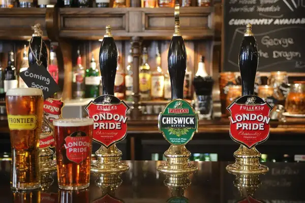 Jak zaplanować zapas piwa na imprezę? Keg vs butelki kalkulacja. Piwo London Pride i Chiswick Bitter na ladzie pubu.