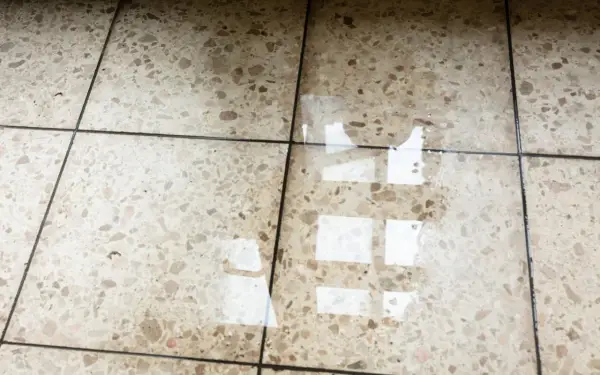Eau sur le sol d'une maison, reflétant la lumière. L'isolation du sol est compromise.