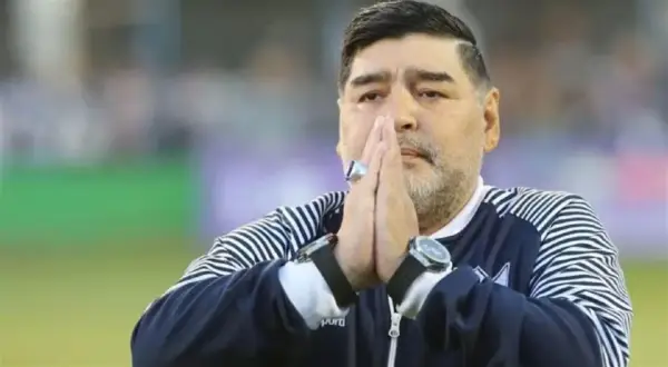 Diego Maradona na co zmarł? Legenda futbolu z dłońmi złożonymi do modlitwy, w charakterystycznej bluzie.