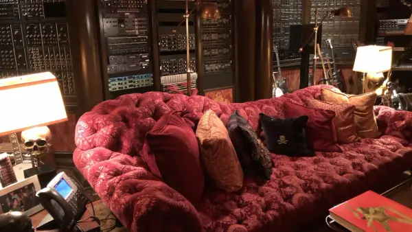 Luxuriöses rotes Samtsofa im Hans Zimmer Studio, umgeben von Musik-Equipment und Gitarren.