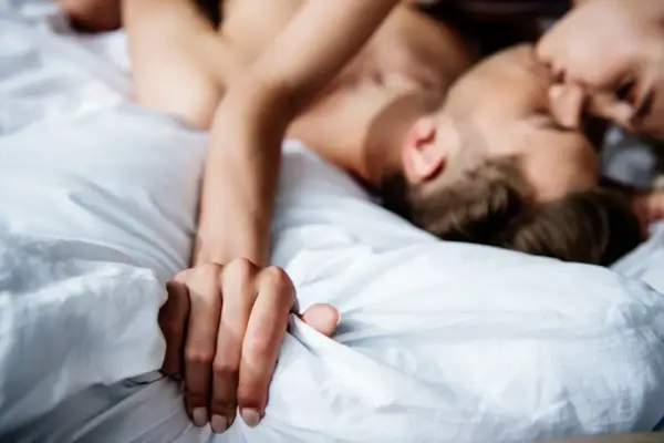 Coppia in intimità, un momento di passione e masturbazione di coppia tra lenzuola bianche.