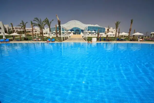 Basen w Hilton Marsa Alam Nubian Resort. Wiele osób odpoczywa na leżakach pod palmami.