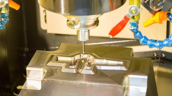 Fresatrice CNC in azione, che lavora un pezzo metallico complesso. Il corso CAD è fondamentale per creare questi dettagli precisi.