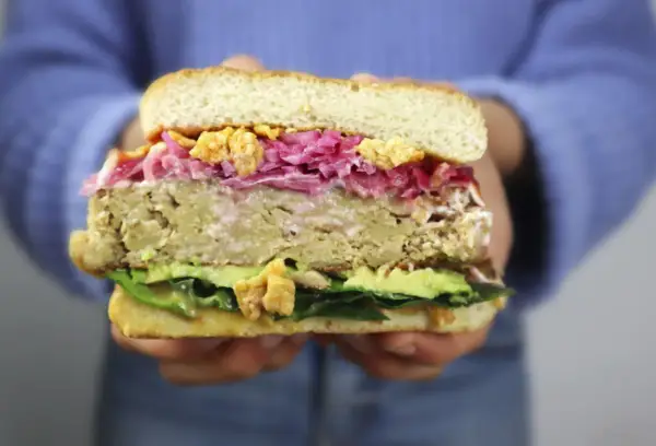 Hamburguesa de pollo con aguacate, col morada y crujientes trozos. ¡Una delicia!