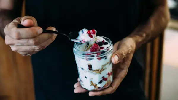 Ein Glas Magerquark mit Beeren, perfekt für den Muskelaufbau. Eine Löffelspitze voller Genuss.